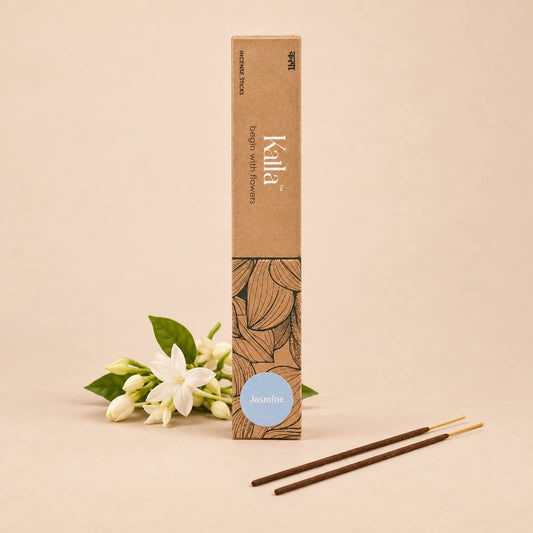 Kalla Jasmine Incense Sticks – natural brown packaging with elegant leaf illustrations and a soft blue label marked “Jasmine,” displayed on a stone surface surrounded by jasmine flowers, brass decor, and incense sticks for a serene, floral-themed ambiance.