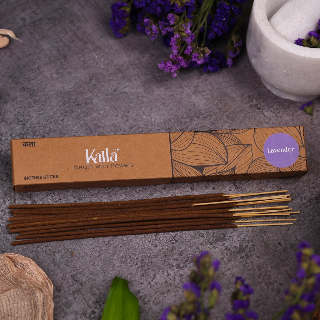 Kalla Lavender Incense Sticks – a natural brown box with floral line art design and a purple label reading “Lavender,” placed on a stone surface with incense sticks laid out, surrounded by fresh lavender flowers and a white mortar for a calming, aromatic setting.