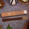 Kalla Tuberose Incense Sticks – eco-friendly brown packaging with artistic floral line designs and a white label marked “Tuberose,” displayed on a textured grey surface with incense sticks arranged neatly, surrounded by natural decorative elements for a serene and floral ambiance.