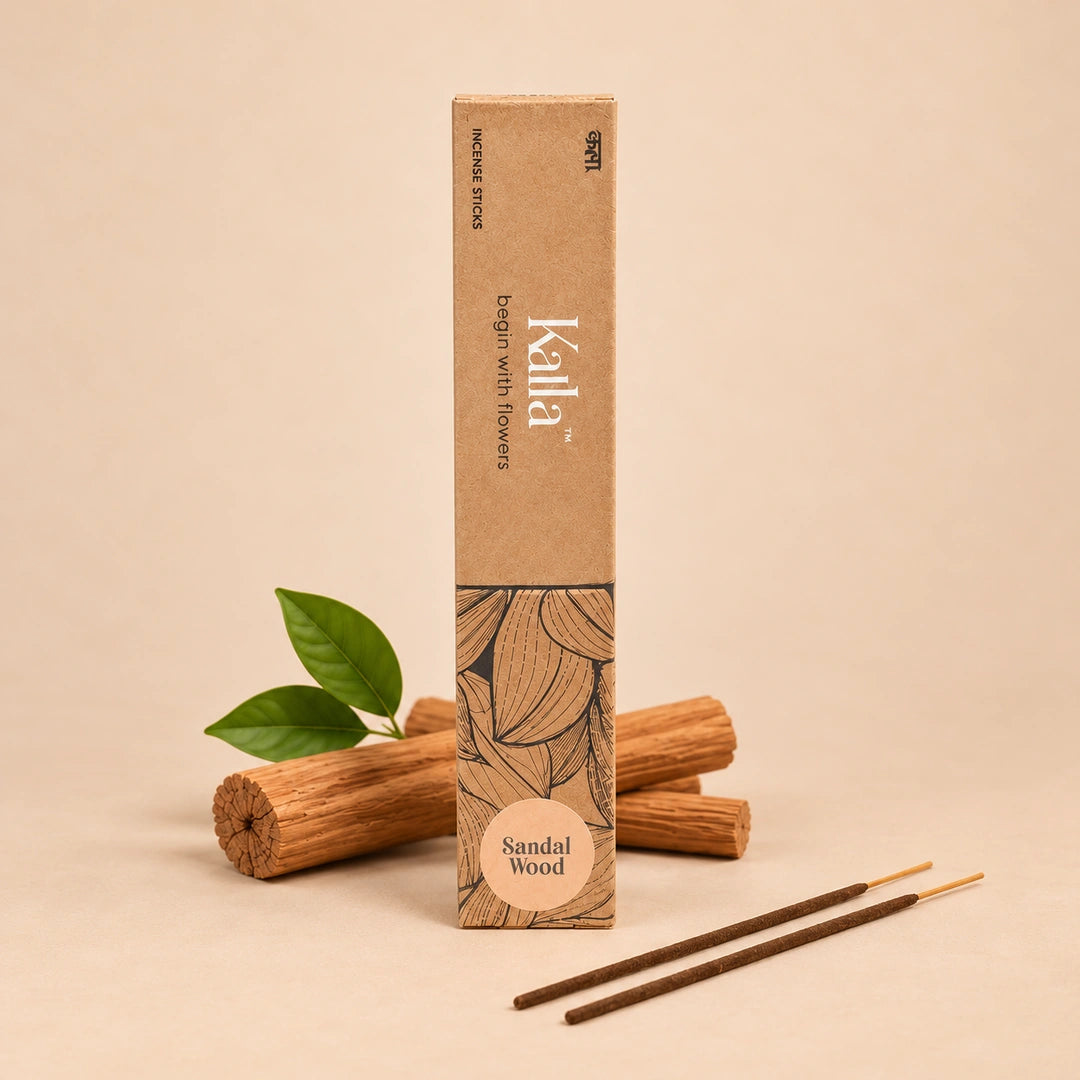 Kalla Sandalwood Incense Sticks – a brown eco-friendly box with floral illustrations, labeled “begin with flowers” and “Sandal Wood,” displayed on a rustic stone background with incense sticks, rose petals, marigold flower, brass incense holder, and traditional decor elements.