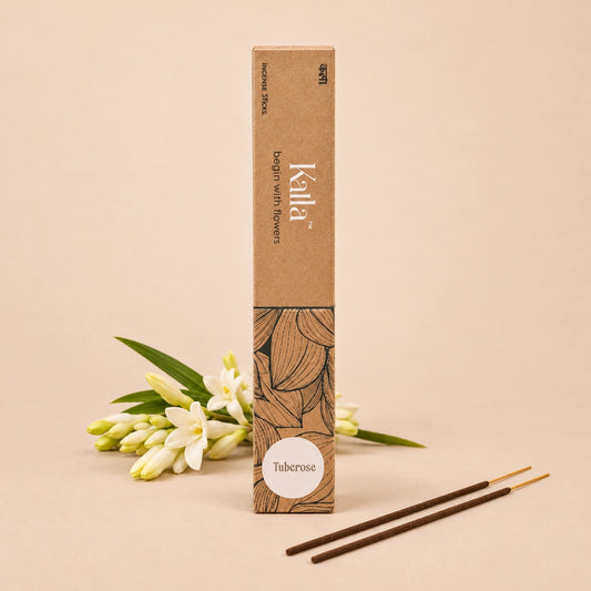 Kalla Tuberose Incense Sticks – eco-friendly brown packaging with artistic floral line designs and a white label marked “Tuberose,” displayed on a textured grey surface with incense sticks arranged neatly, surrounded by natural decorative elements for a serene and floral ambiance.