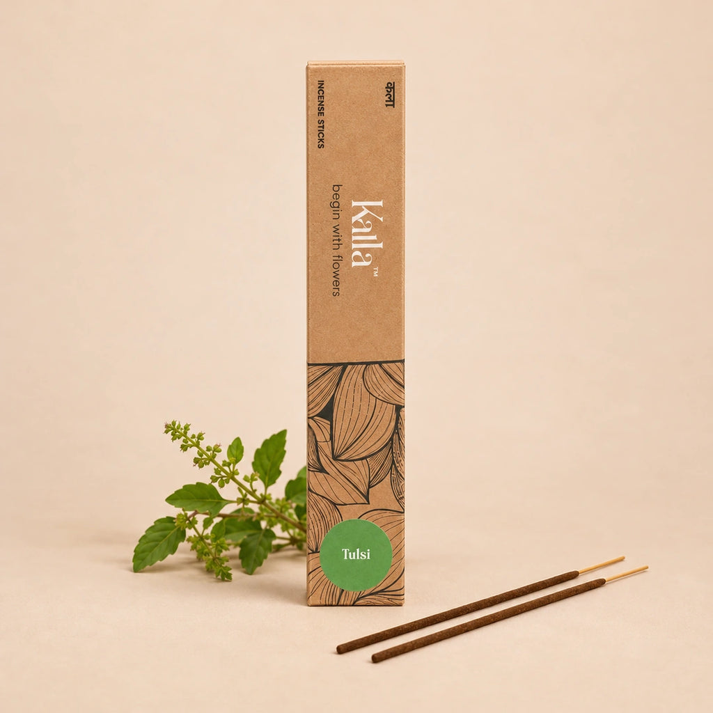 Kalla Tulsi Incense Sticks – eco-friendly brown packaging with intricate floral line art and a green label reading “Tulsi,” displayed on a grey stone surface with incense sticks laid out, surrounded by traditional brass vessels, tulsi leaves, and a serene ritual setting.